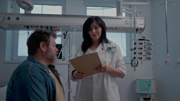 A doctor explaining the risks of leaving the hospital early as the patient prepares to sign an AMA form.