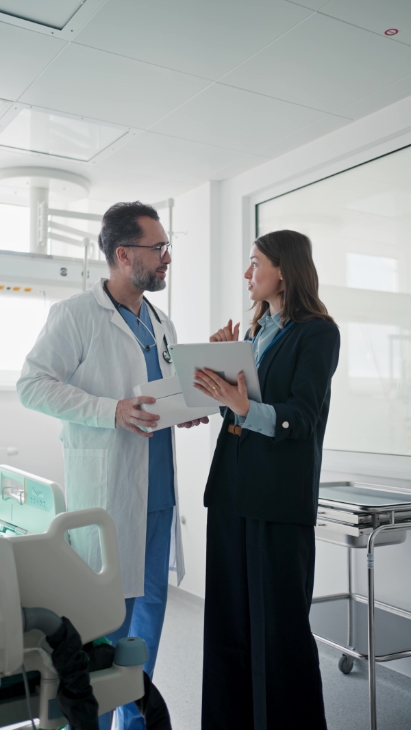 Pharmaceutical sales respresentative with doctor, hospital setting.