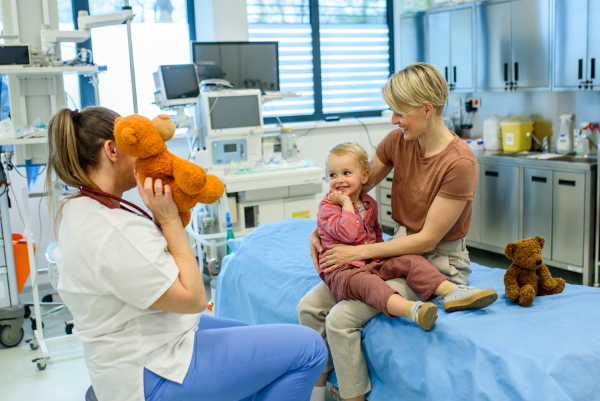 Female pediatrician comforting little boy with teddy bear during checkup