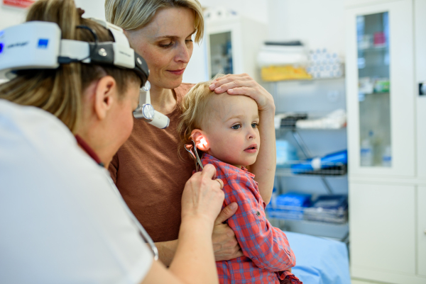 Otolaryngologist examining toddler in pediatric clinic, ENT exam.