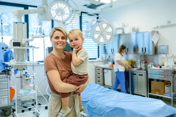 Portrait of beautiful mother with little toddler son during examination in medical clinic. Preventive care.