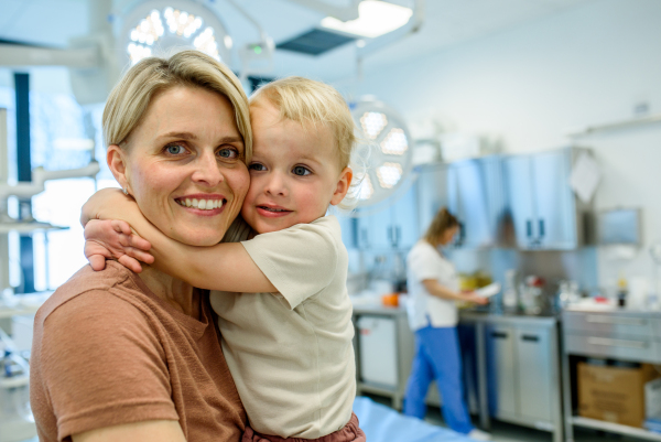 Portrait of beautiful mother with little toddler son during examination in medical clinic. Preventive care.