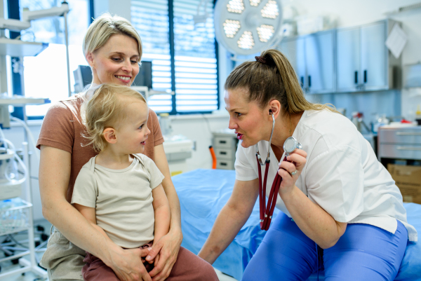 Female doctor listening little boy's heartbeat and breathing during preventive medical checkup.