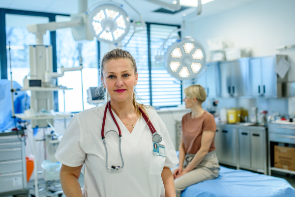 Female doctor in face mask standing in examination room.