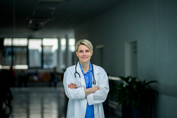 Young female doctor with short hair in hospital corridor, smiling, looking at camera.