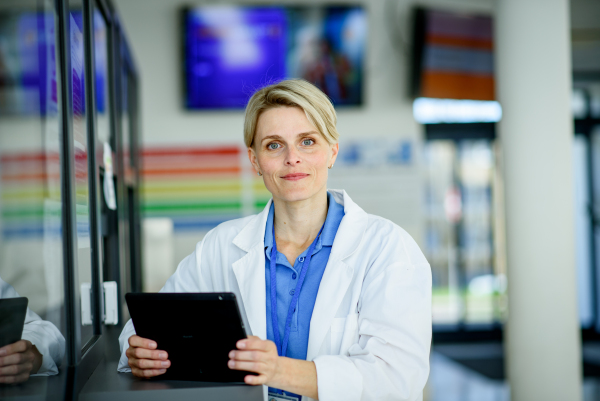 Young female doctor with short hair in hospital corridor, smiling, looking at camera.