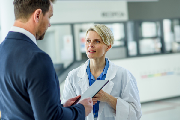 Doctor and pharmaceutical representative talking about new drug in clinical setting.