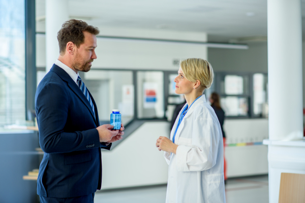 Doctor and pharmaceutical representative talking about new drug in clinical setting.