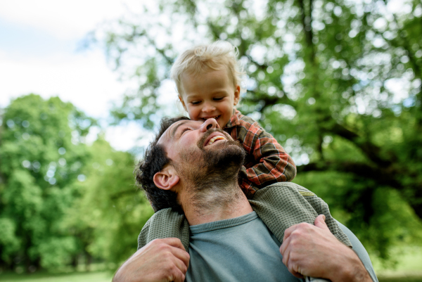 Dad carrying his smiling son on shoulders during walk in park