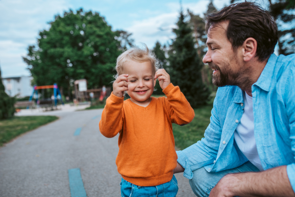 Father playing with toddler son outdoors in city park