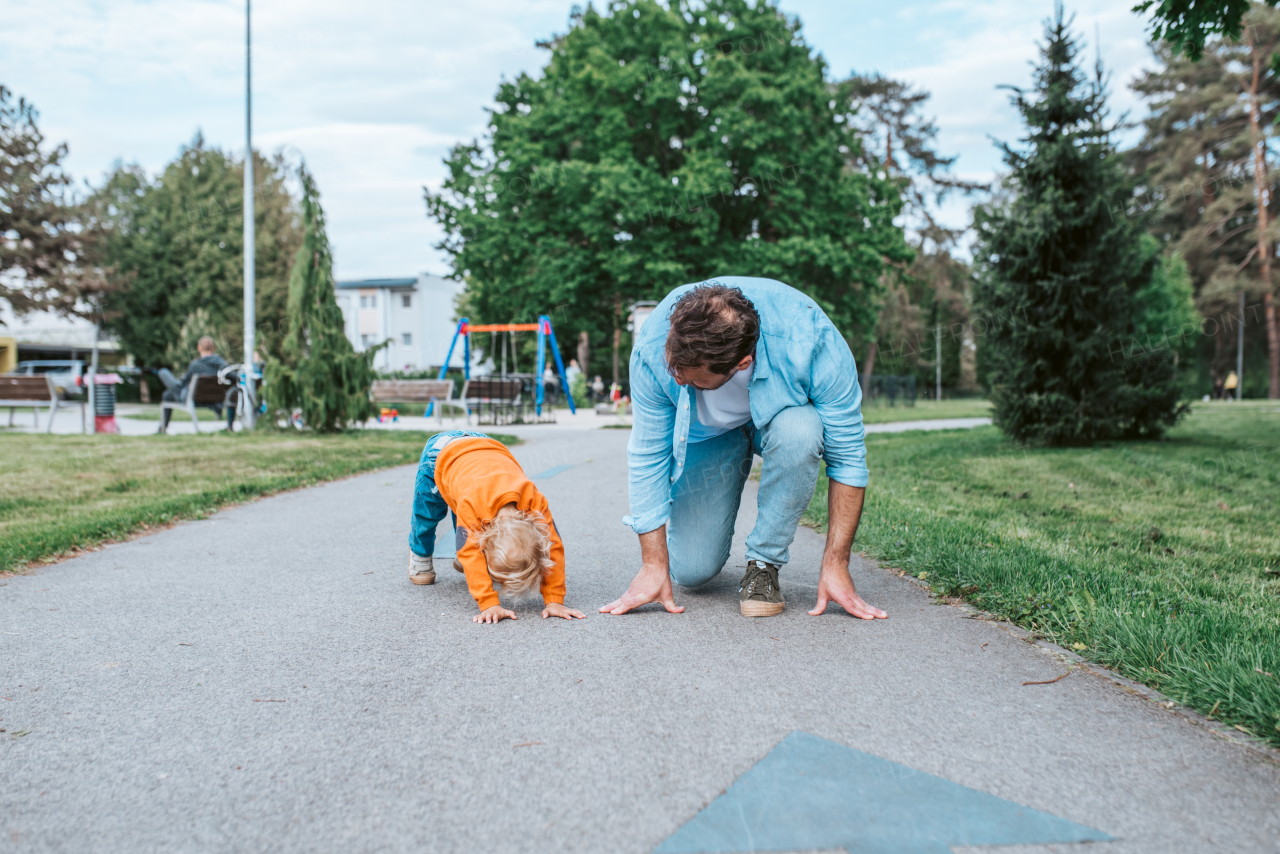 Father lining up to have a running race with his young son.
