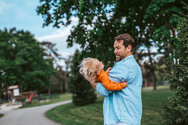 Father playing with toddler son outdoors in city park