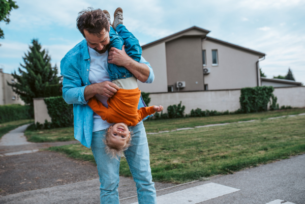 Father playing with toddler son, holding him upside down. Fun time.