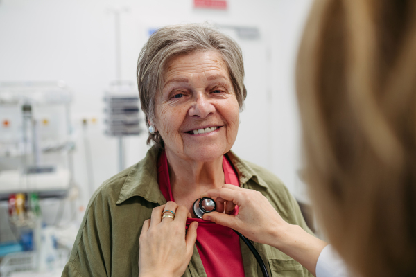 Geriatrician doctor examining elderly patient with stethoscope.. Routine health exam for elderly woman.