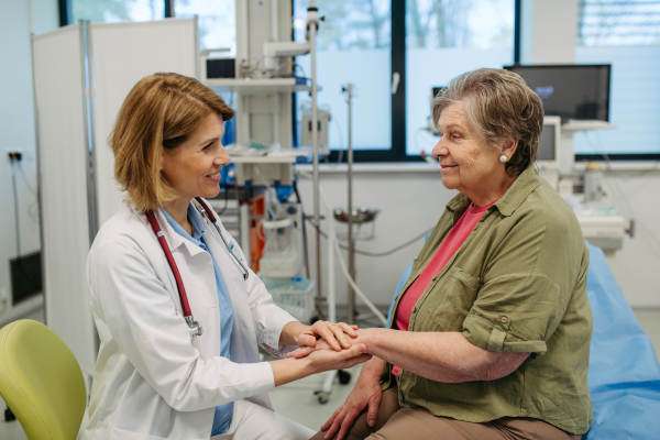 Caring doctor holding senior patient hand, compassionate gesture.