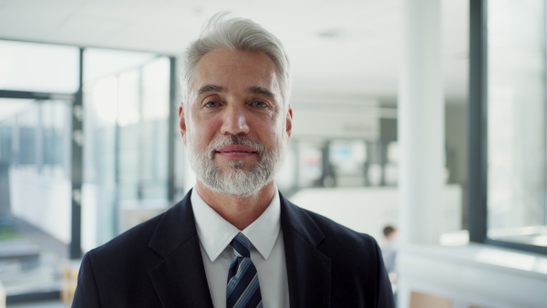 Confident senior manager holding documents in modern clinic or office environment.