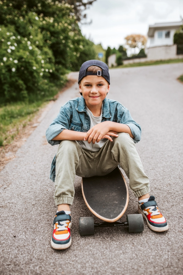 Cute Boy sitting on his longboard on street, enjoying holidays.
