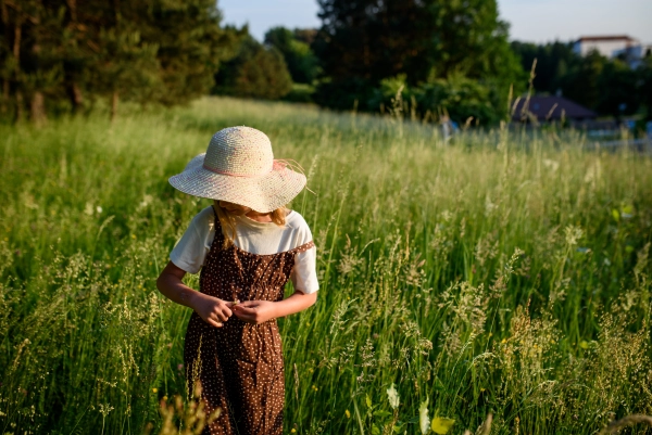 Child walking through tall grass in countryside, peaceful childhood moment.