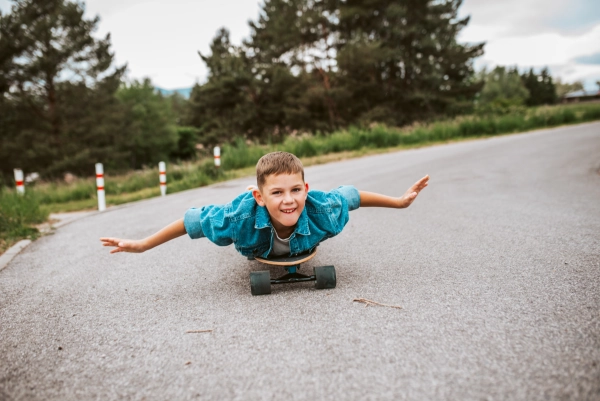 Young boy riding longborad while lying on it, having fun.