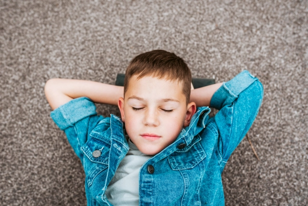Relaxed boy lying on ground with closed eyes