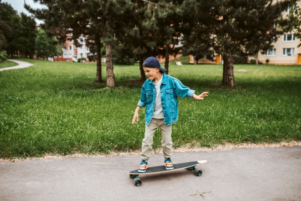 Young boy Learning to ride a longboard on the street.