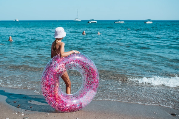 Girl on beach with swim ring. Summer beach holiday.