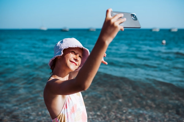 Girl taking selfie on beach with smartphone, summer beach holiday concept.