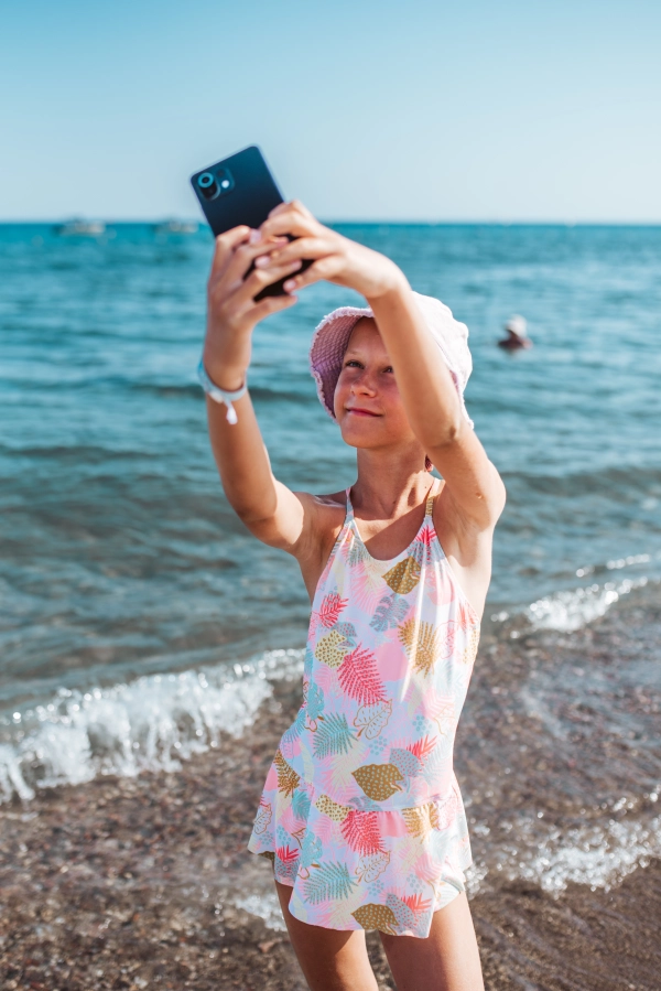Girl taking selfie on beach with smartphone, summer beach holiday concept.