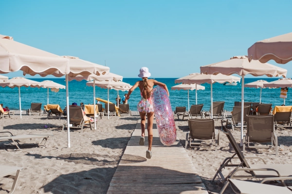 Girl running to the beach with swim ring in hand. Summer beach holiday.