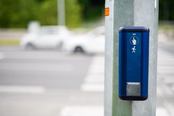 Pedestrian crossing button on traffic light pole at urban intersection