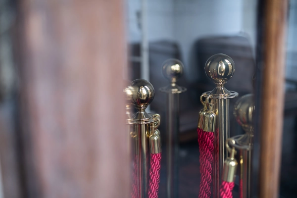 Elegant detail of brass stanchions with red velvet ropes behind glass