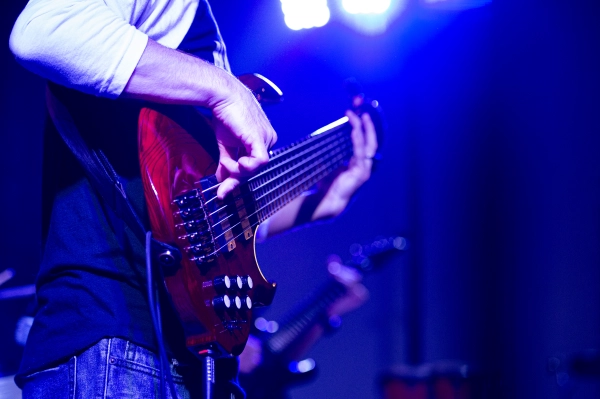 Live bass guitar performance at night concert.