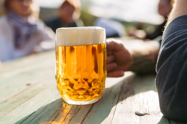 Close up of hand holding glasses of bubbling and foaming beer.